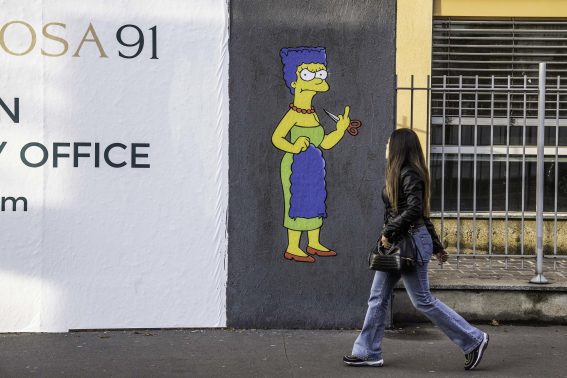 Una passante di Milano vicino a un murales di protesta contro il regime iraniano Una passante di Milano vicino a un murales di protesta contro il regime iraniano