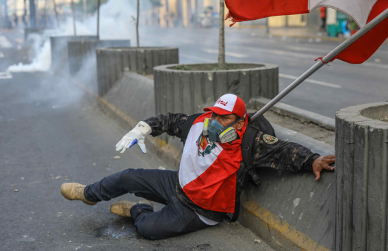 Un manifestante accasciato a terra è dotato di maschera antigas a seguito dell'utilizzo di lacrimogeni da parte della polizia