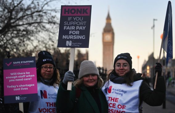 Infermieri NHS davanti il St.Thomas Hospital a Londra. Sul cartello: "Suona il clacson se sei a favore di una giusta paga per gli infermieri".