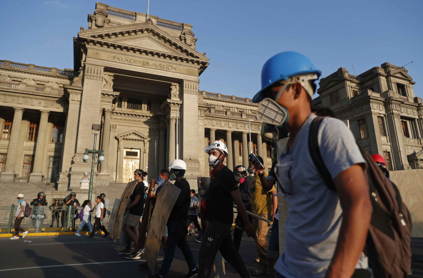 Protestanti in maschera marciano nei pressi del Palazzo di Giustizia a Lima