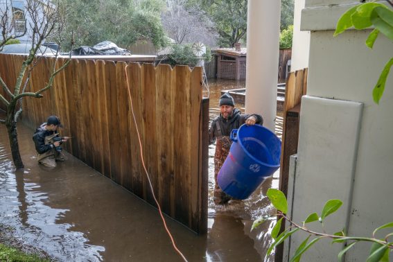 Un uomo cerca di liberare dall'acqua il proprio cortile
