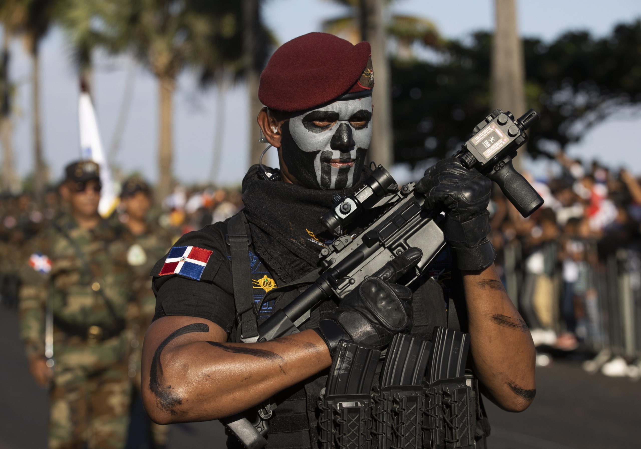 Un militare domenicano, con un teschio dipinto sul volto, imbraccia un fucile
