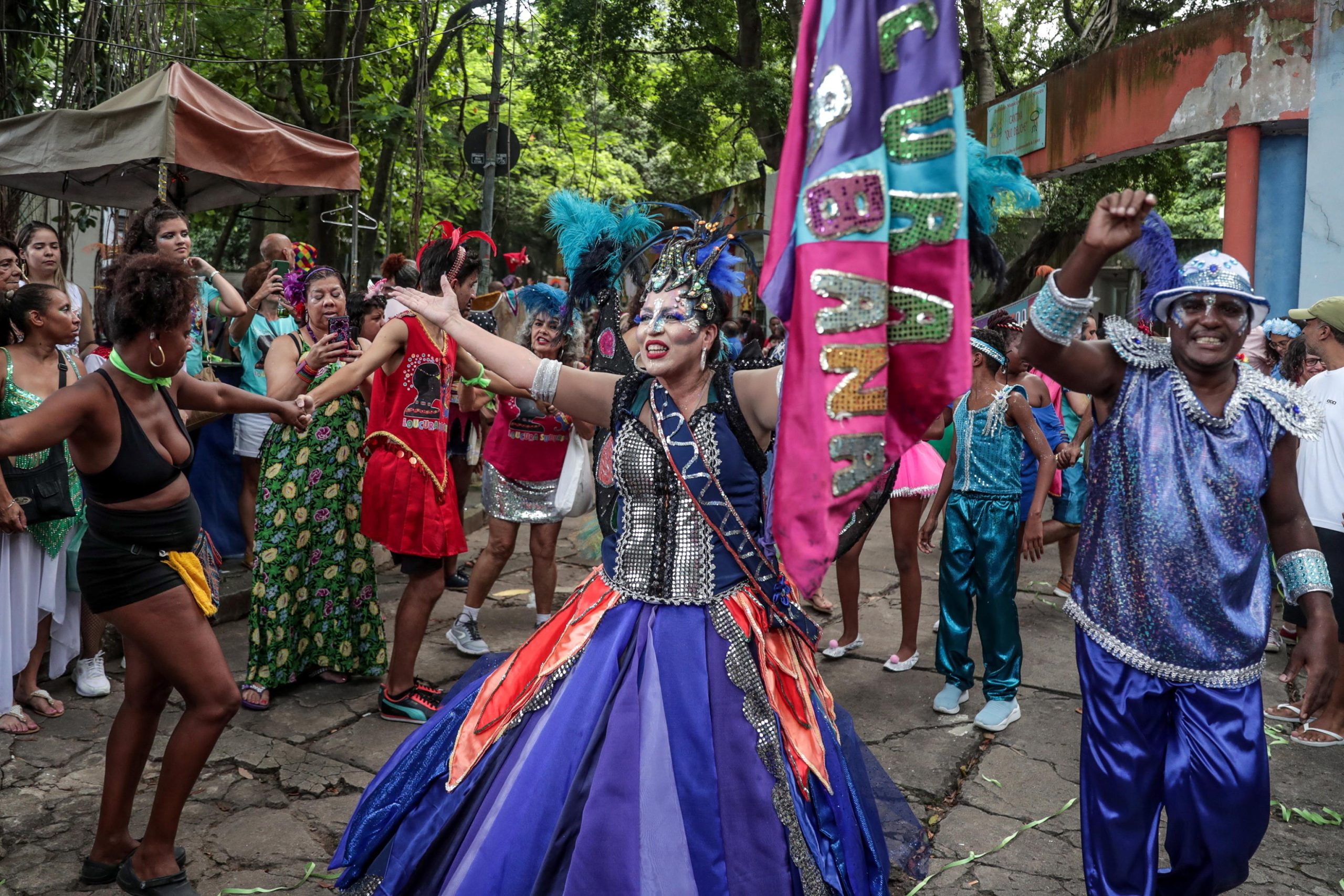 Una donna in abiti carnevaleschi sfila per le strade di Rio, intorno a lei una folla danzante di partecipanti