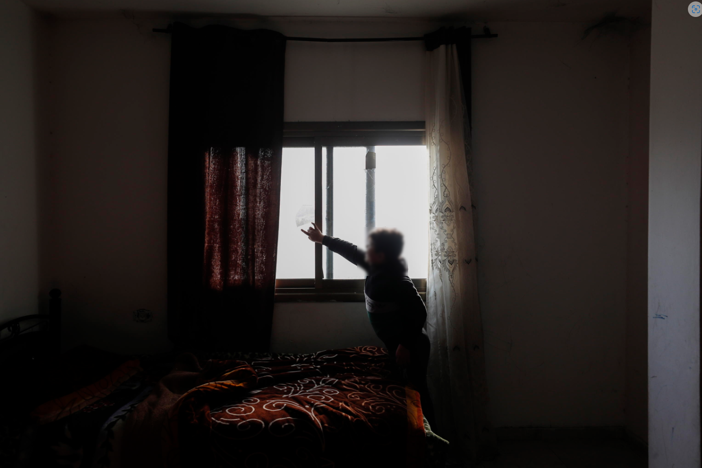 Un ragazzo palestinese mostra i danni alla finestra della sua camera da letto