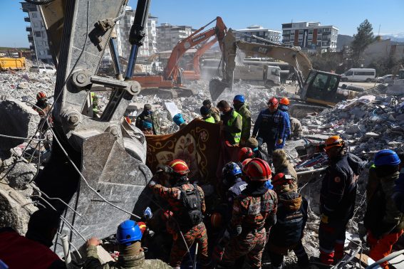I membri della squadra di soccorso lavorano tra le macerie di un edificio crollato dopo un terremoto a Nurdagi, uno dei distretti della provincia di Gaziantep, in Turchia