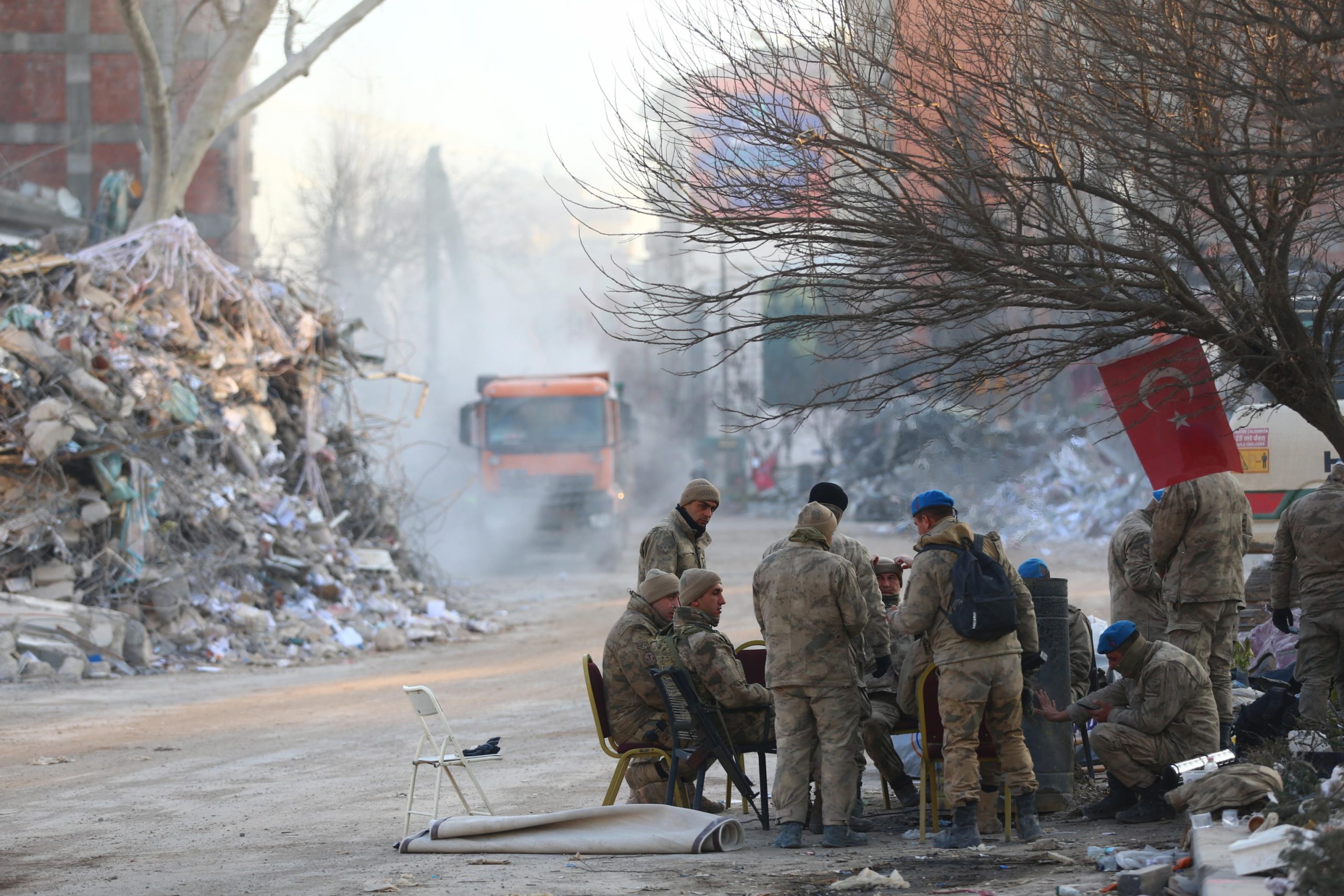 Alcuni soldati turchi si riposano vicino i resti di un palazzo dopo un terremoto a Kahramanmaras, in Turchia
