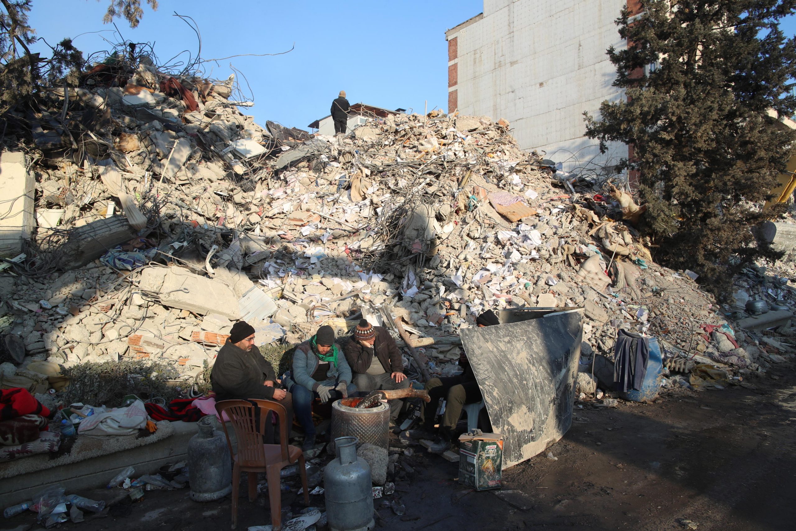Alcuni familiari di persone scomparse si riscaldano nell'attesa dei soccorsi a Kahramanmaras in Turchia