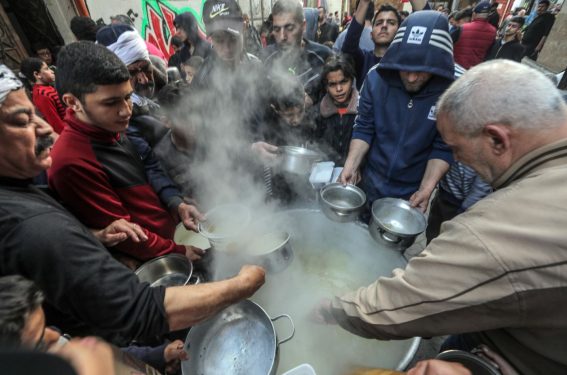 Alcuni palestinesi cercano di ricevere un piatto di zuppa, a Gaza City nella Striscia di Gaza, il 24 marzo 2023