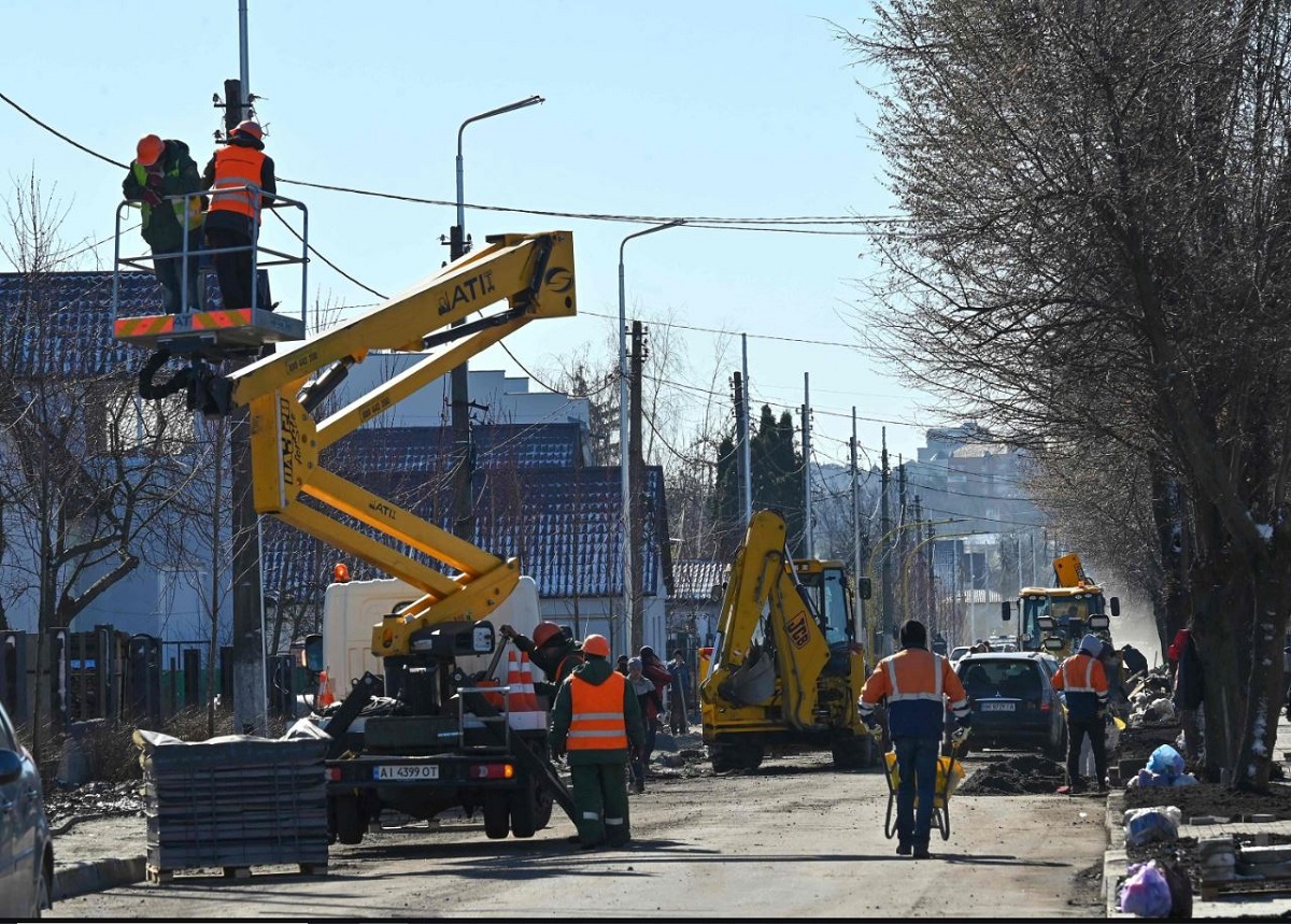 Uomini riparano la strada di Vokzalna a Bucha, 31 marzo 2023.