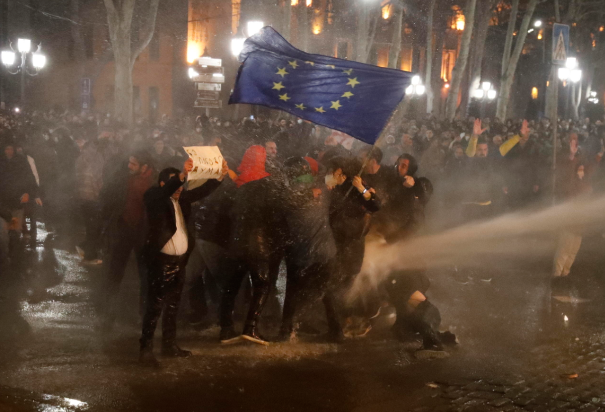Una donna sventola la bandiera Ue mentre resiste agli idranti Una donna sventola la bandiera Ue mentre resiste agli idranti