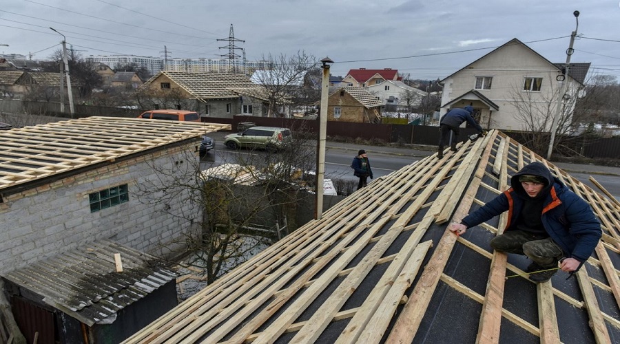 Costruttori riparano il tetto di una casa danneggiato dal bombardamento a Bucha in Ucraina, 11 Febbraio 2023.