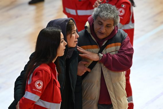 Membri della Croce Rossa accompagnano una donna alla camera ardente