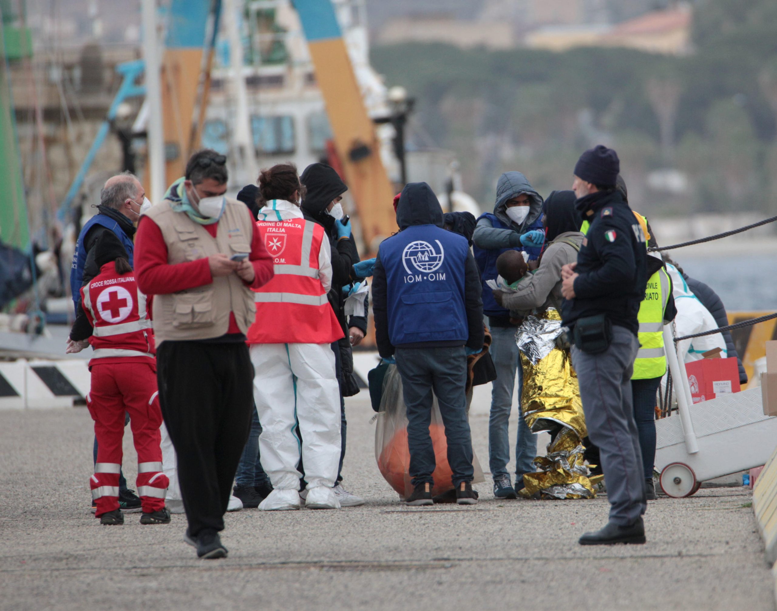 I soccorritori mentre aiutano i 589 migranti sbarcati a Reggio Calabria