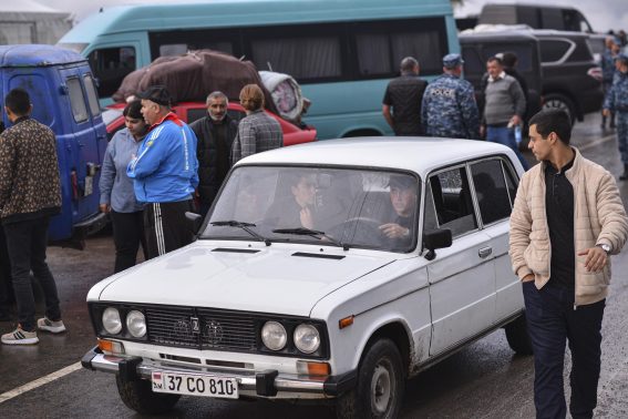 Una macchina vecchia attraversa i confini armeni sotto lo sguardo di altri profughi