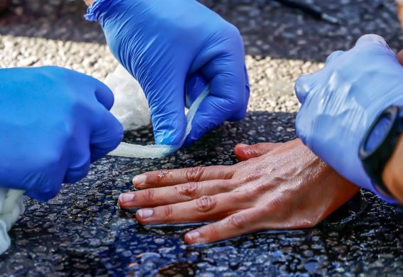 Un poliziotto prova a rimuovere la colla dalla mano di un attivista
