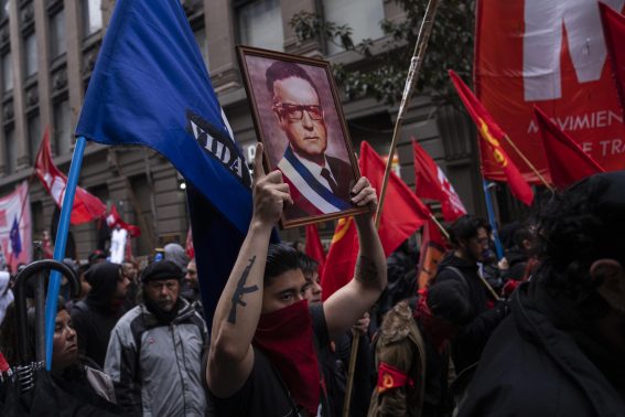Un manifestante tiene in alto una foto di Salvador Allende il cui governo fu rovesciato dal golpe di Pinochet