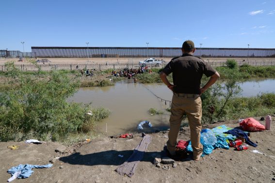 Un funzionario di frontiera osserva i migranti che tentano di attraversare il Rio Grande