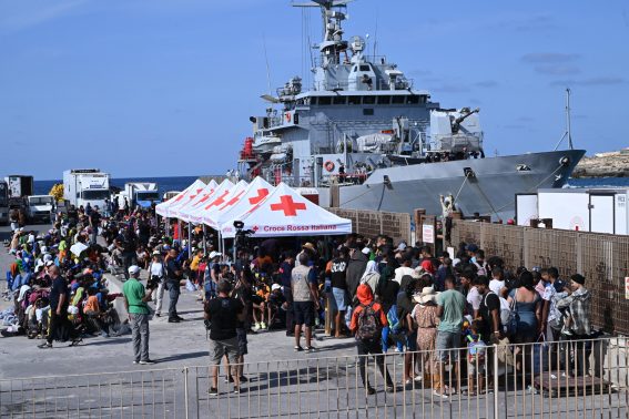 Le lunghe file di migranti in attesa di essere trasferiti da Lampedusa