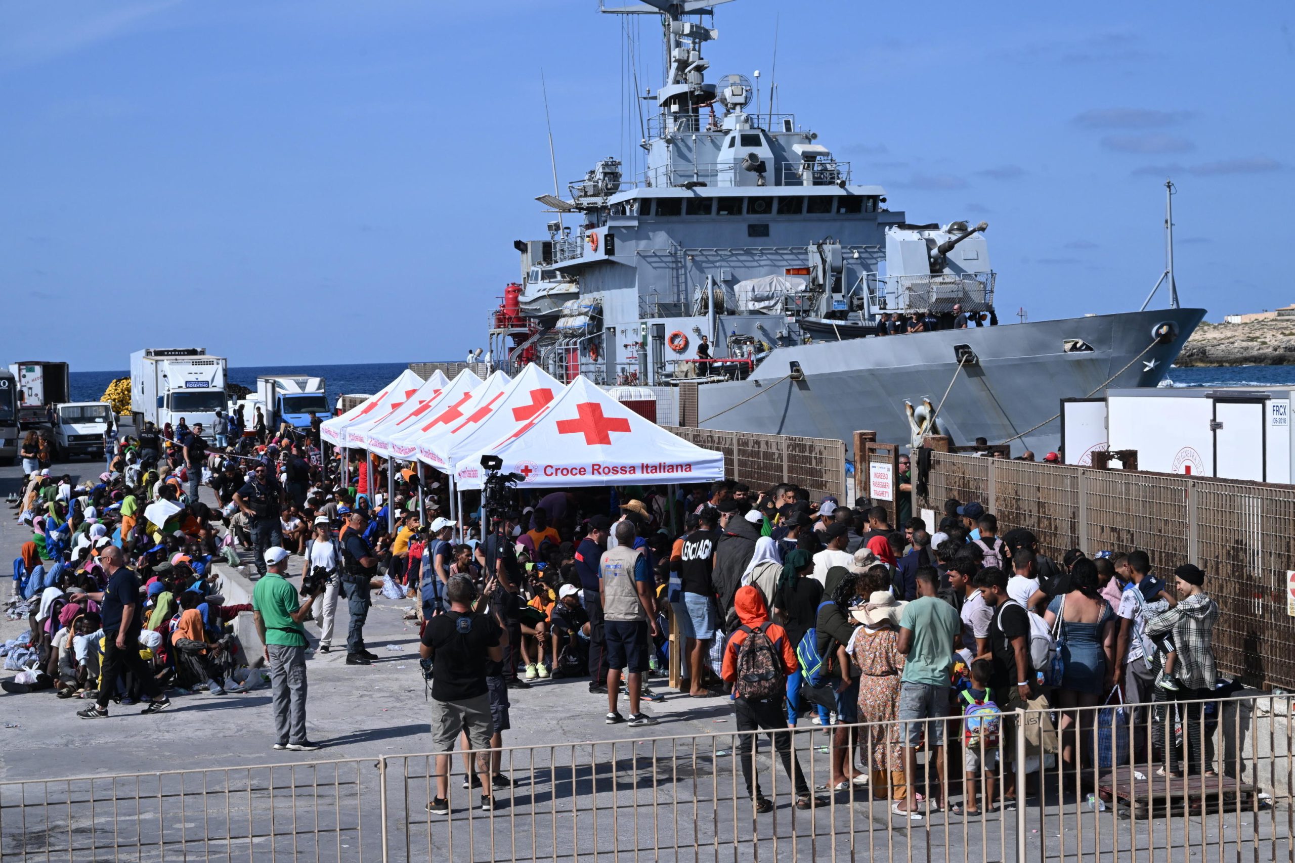 Le lunghe file di migranti in attesa di essere trasferiti da Lampedusa