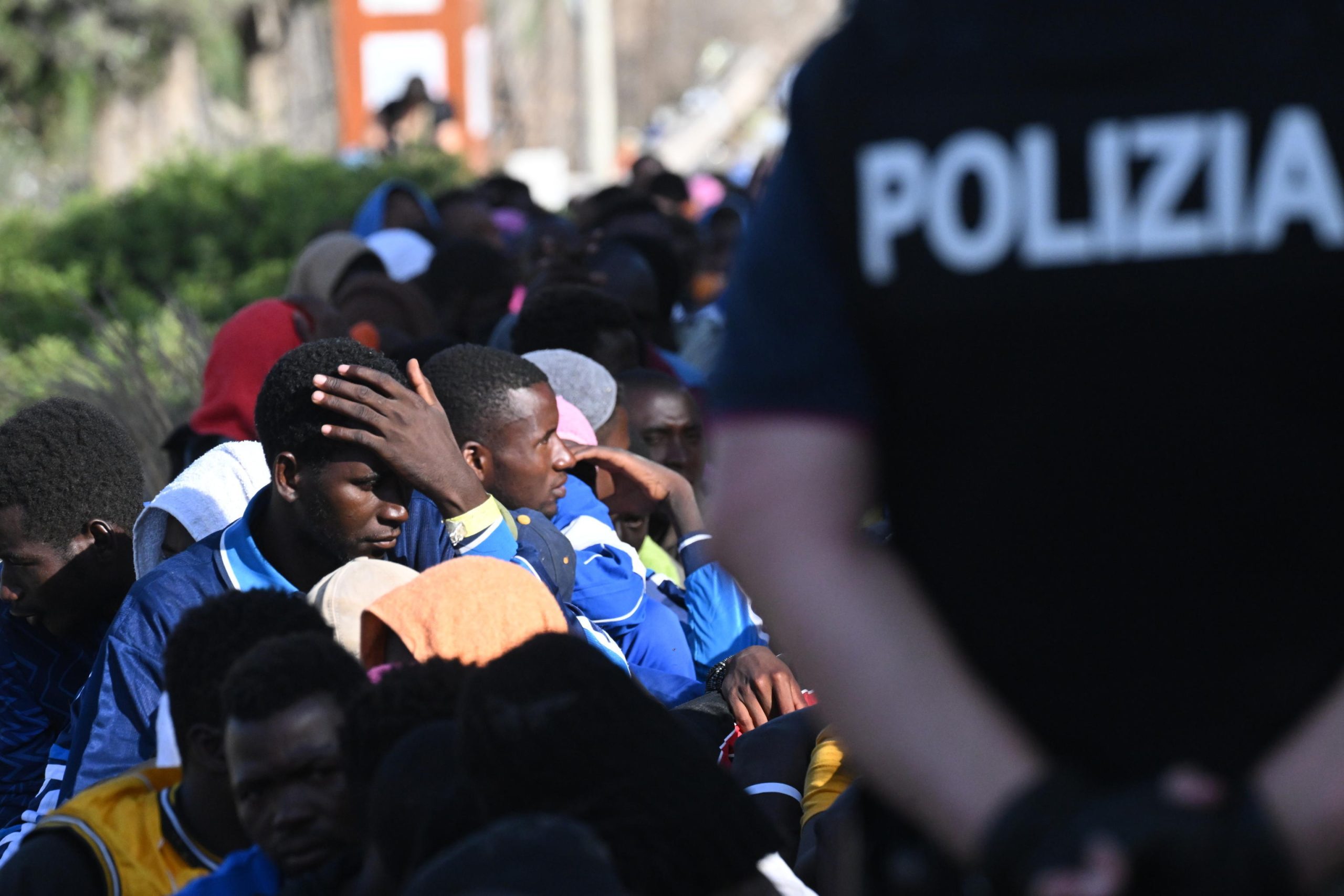 I migranti attendono i controlli sotto lo sguardo della polizia italiana