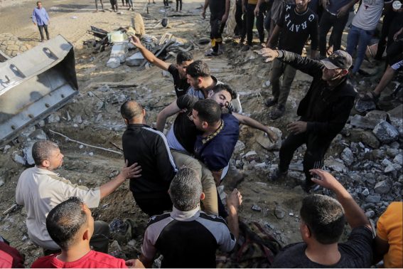 Palestinesi cercano i sopravvissuti tra le macerie di un edificio raso al suolo da un attacco israeliano