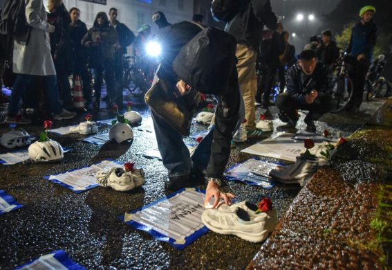 Un partecipante al flash-mob accende una candela su un manifesto di un pedone deceduto