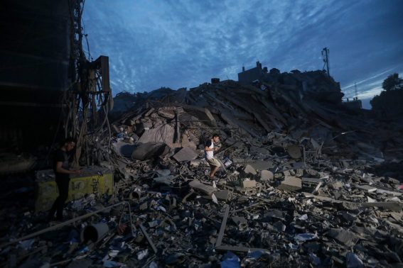 Un uomo passa sulle macerie della Torre Palestina di Gaza dopo il suo abbattimento da parte dell'aviazione israeliana.