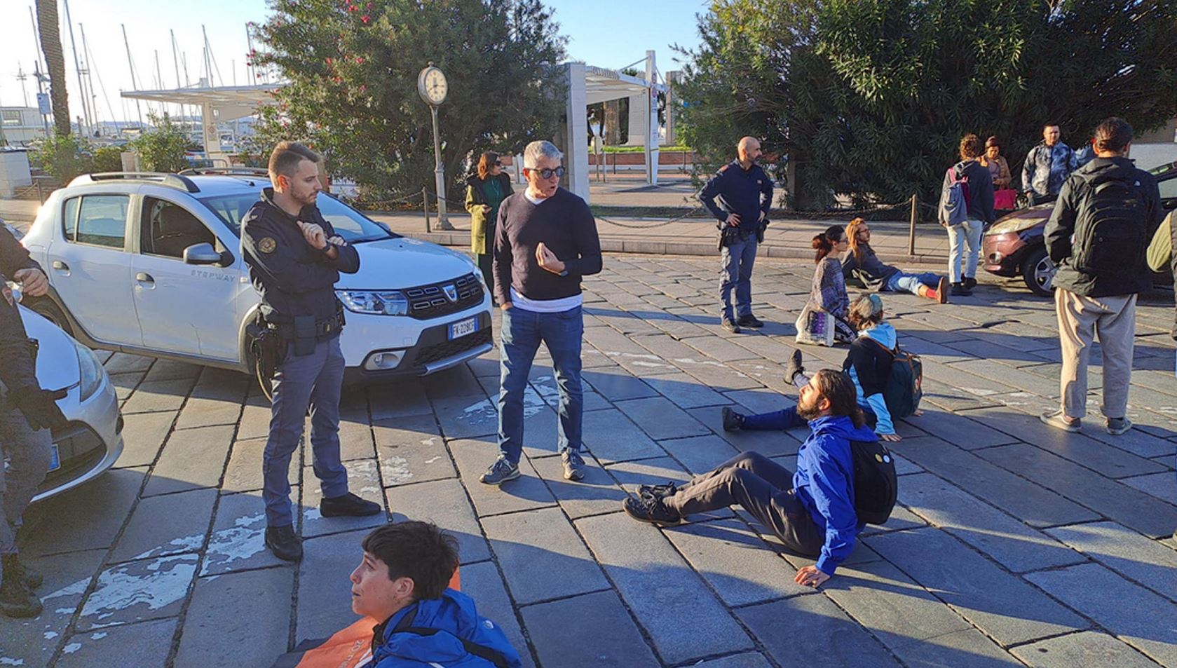 La polizia parla con gli attivisti di Ultima Generazione seduti sulla strada a Cagliari