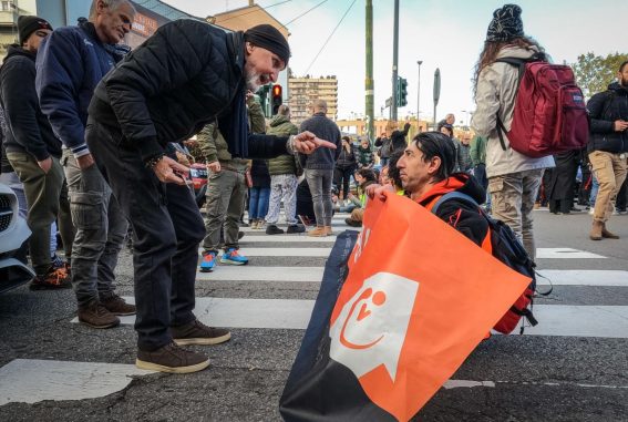 Passante punta il dito contro un attivista di Ultima Generazione seduto sull'asfalto in viale Lucania a Milano