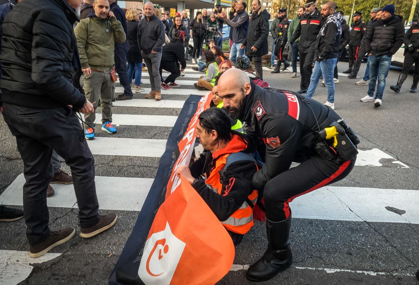 Un carabiniere preleva un manifestante che tiene un lembo dello striscione sul Fondo Riparazione a Milano