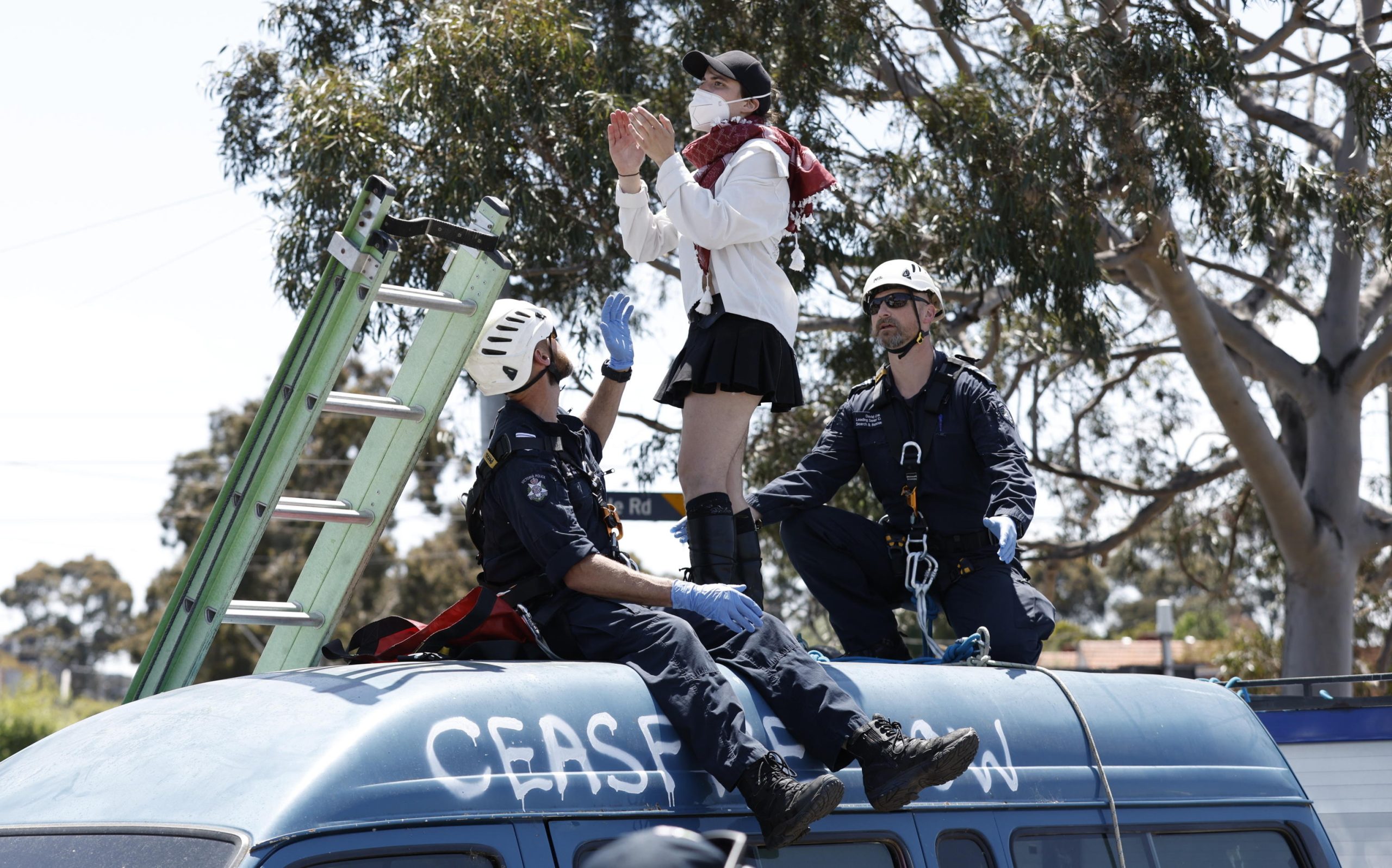 Una manifestante protesta sopra un furgone mentre due poliziotti le intimano di scendere a Melbourne