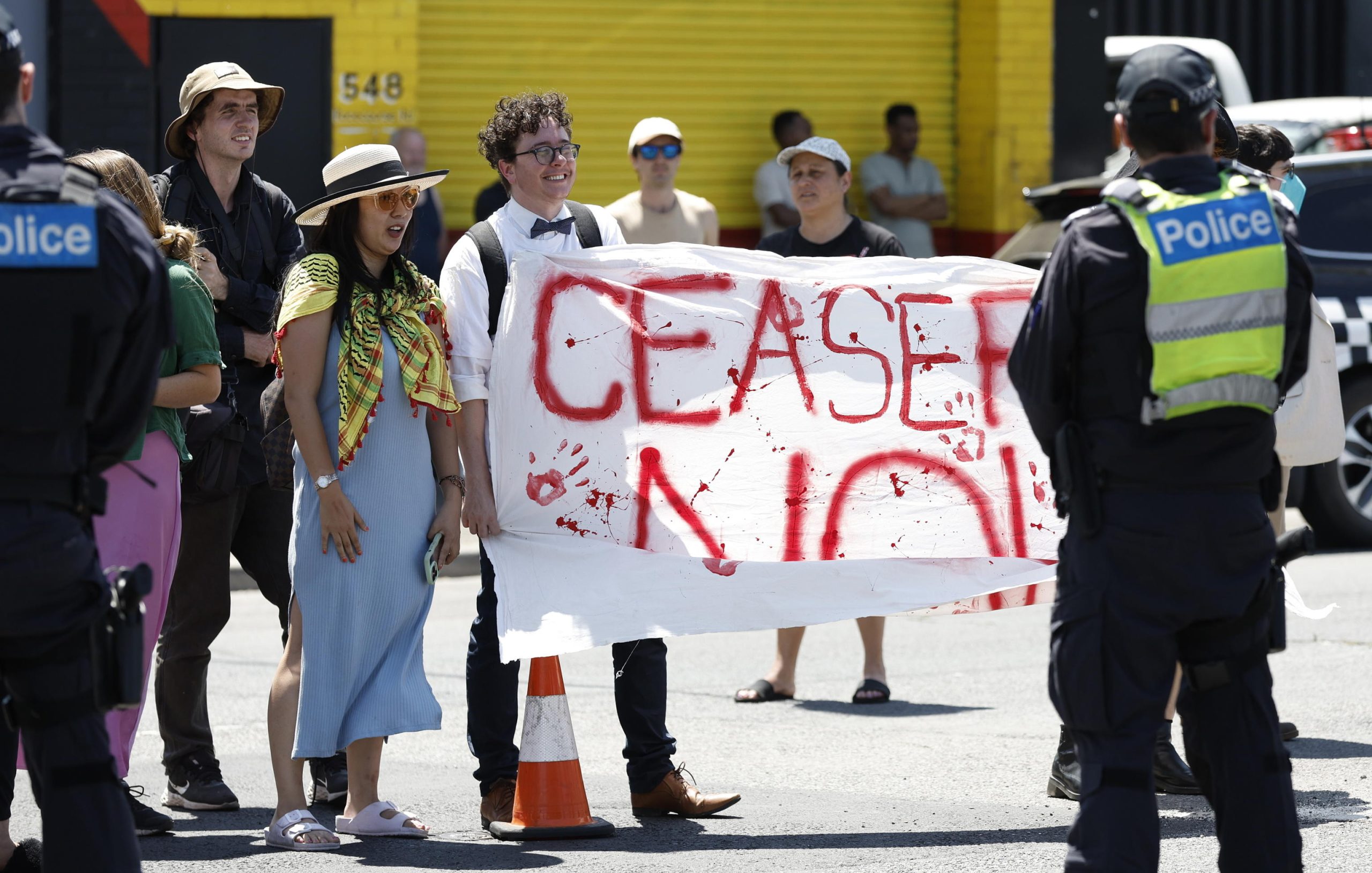 Alcuni manifestanti protestano con uno striscione che simula chiazze di sangue rosse