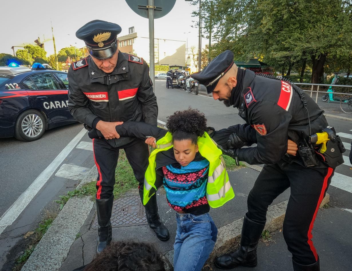 Due carabinieri portano via di peso una manifestante di Ultima Generazione a Milano