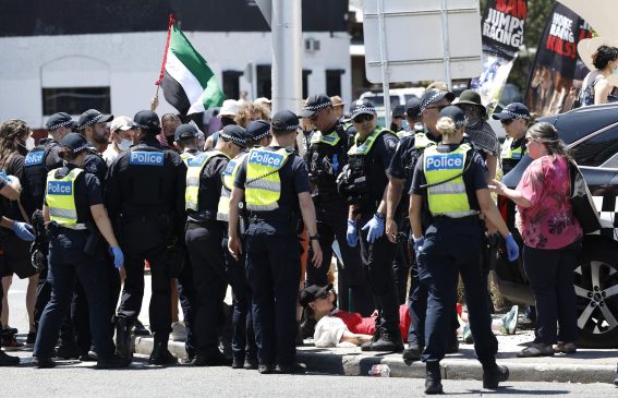 Uomini della polizia circondano un gruppo di manifestanti pro Palestina durante il Melbourne Cup Day