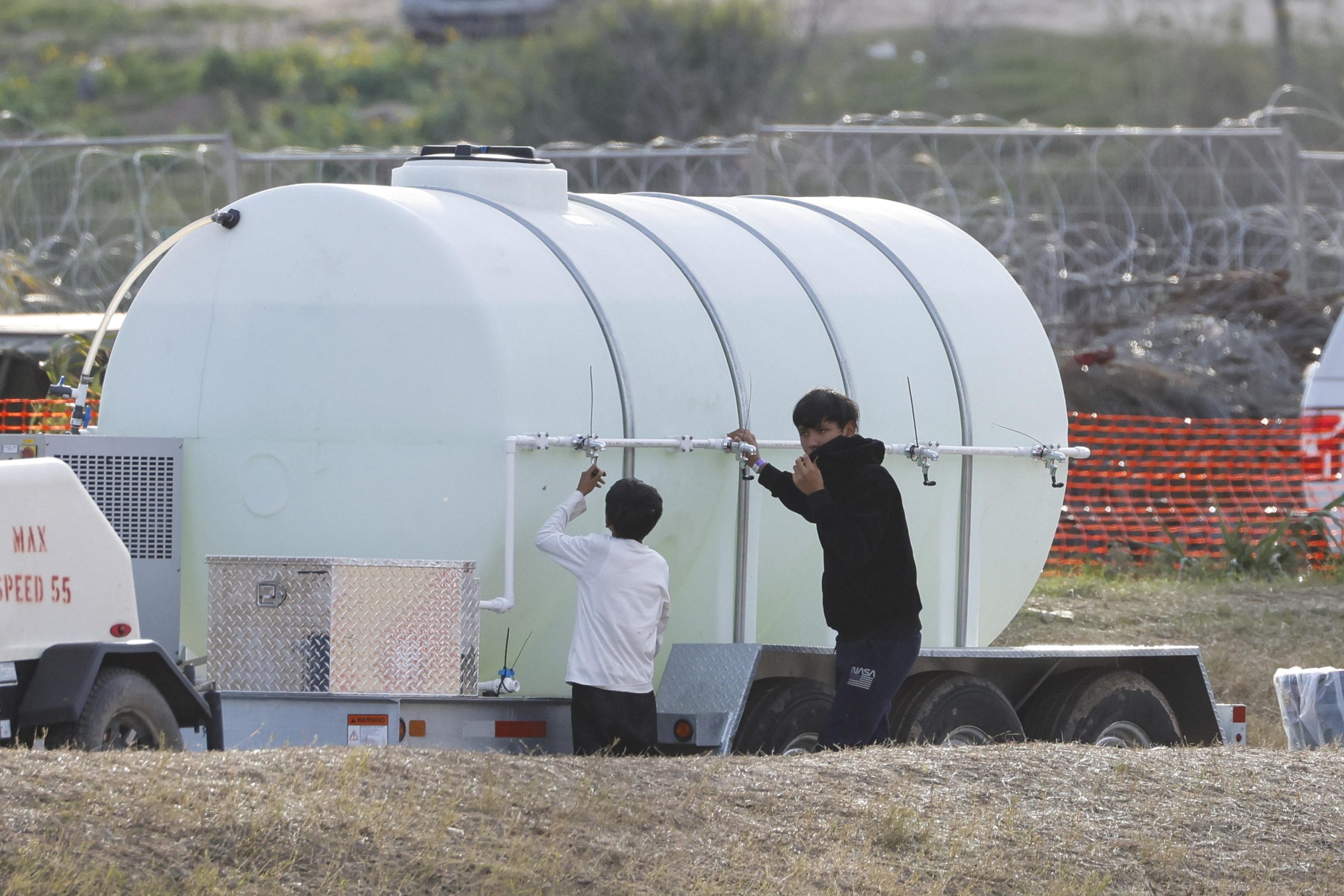 Due giovani migranti si riforniscono a un serbatoio d'acqua allo Shelby Park di Eagle Pass, Texas, USA