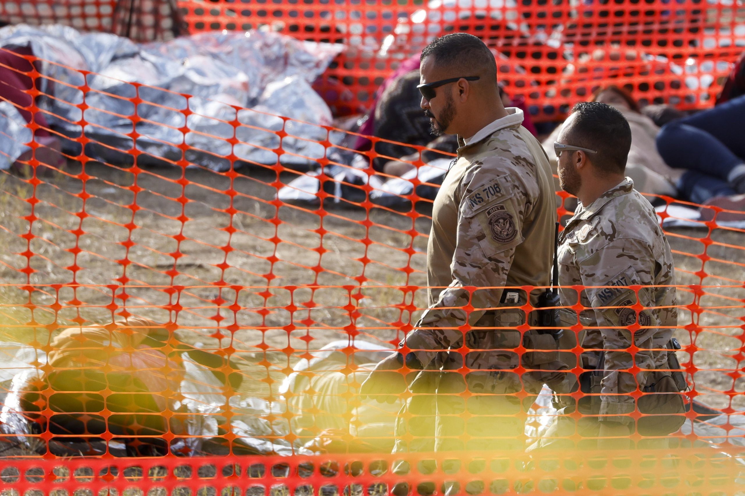 Agenti della dogana passano accanto a migranti sdraiati sul terreno dello Shelby Park di Eagle Pass, Texas, USA Agenti della dogana passano accanto a migranti sdraiati sul terreno dello Shelby Park di Eagle Pass, Texas, USA