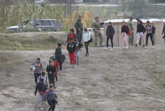Migranti in fila mentre scendono da una collina a Shelby Park a Eagle Pass, Texas, USA