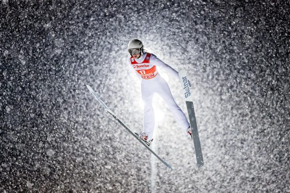 La romena Daniela Haralambie durante la FIS Ski Jumping World Cup in Svizzera. Il salto crea una nuvola di neve attorno all'atleta