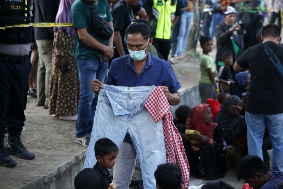 La gente del posto dona vestiti ai rifugiati Rohingya che si rifugiano davanti all'ufficio del governatore di Aceh a Banda Aceh, Indonesia