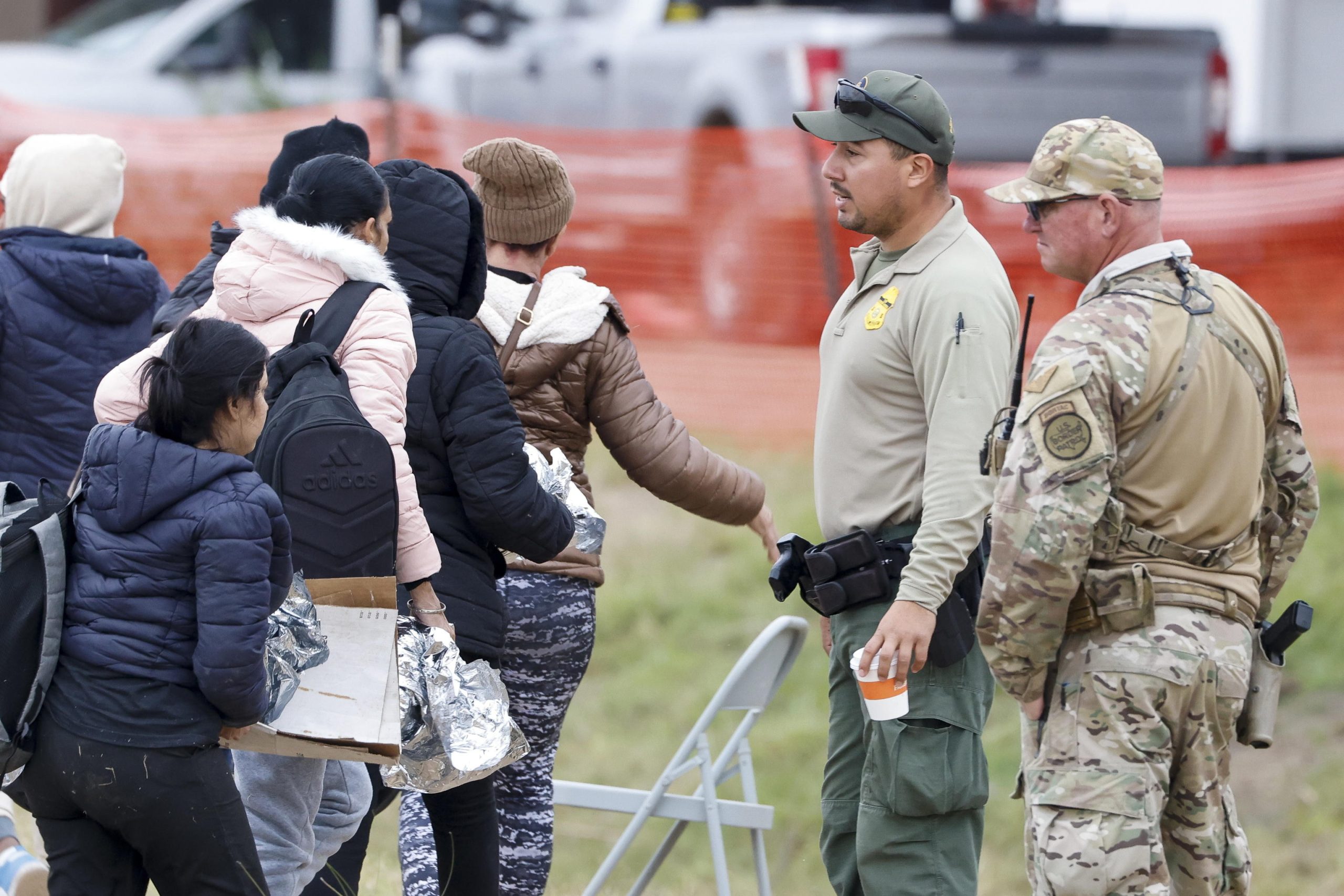 Migranti passano davanti a un agente della polizia di frontiera e a una guardia nazionale del Texas allo Shelby Park di Eagle Pass, Texas, USA Migranti passano davanti a un agente della polizia di frontiera e a una guardia nazionale del Texas allo Shelby Park di Eagle Pass, Texas, USA