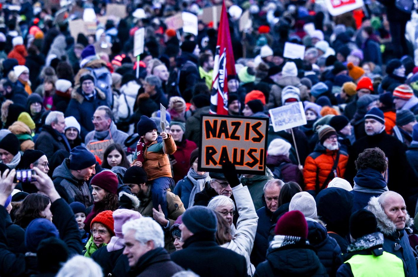 Un cartello recita "Fuori i nazisti" mentre i manifestanti partecipano al corteo