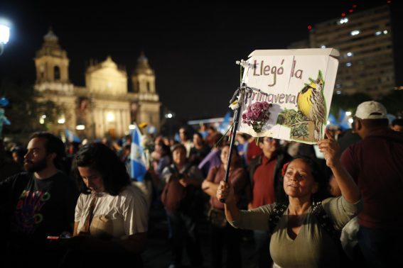 Una cittadina guatemalteca mentre mostra un cartello con la scritta "Llegò la primavera" (è arrivata la primavera).
