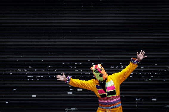 Un clown mascherato in posa davanti a una saracinesca abbassata