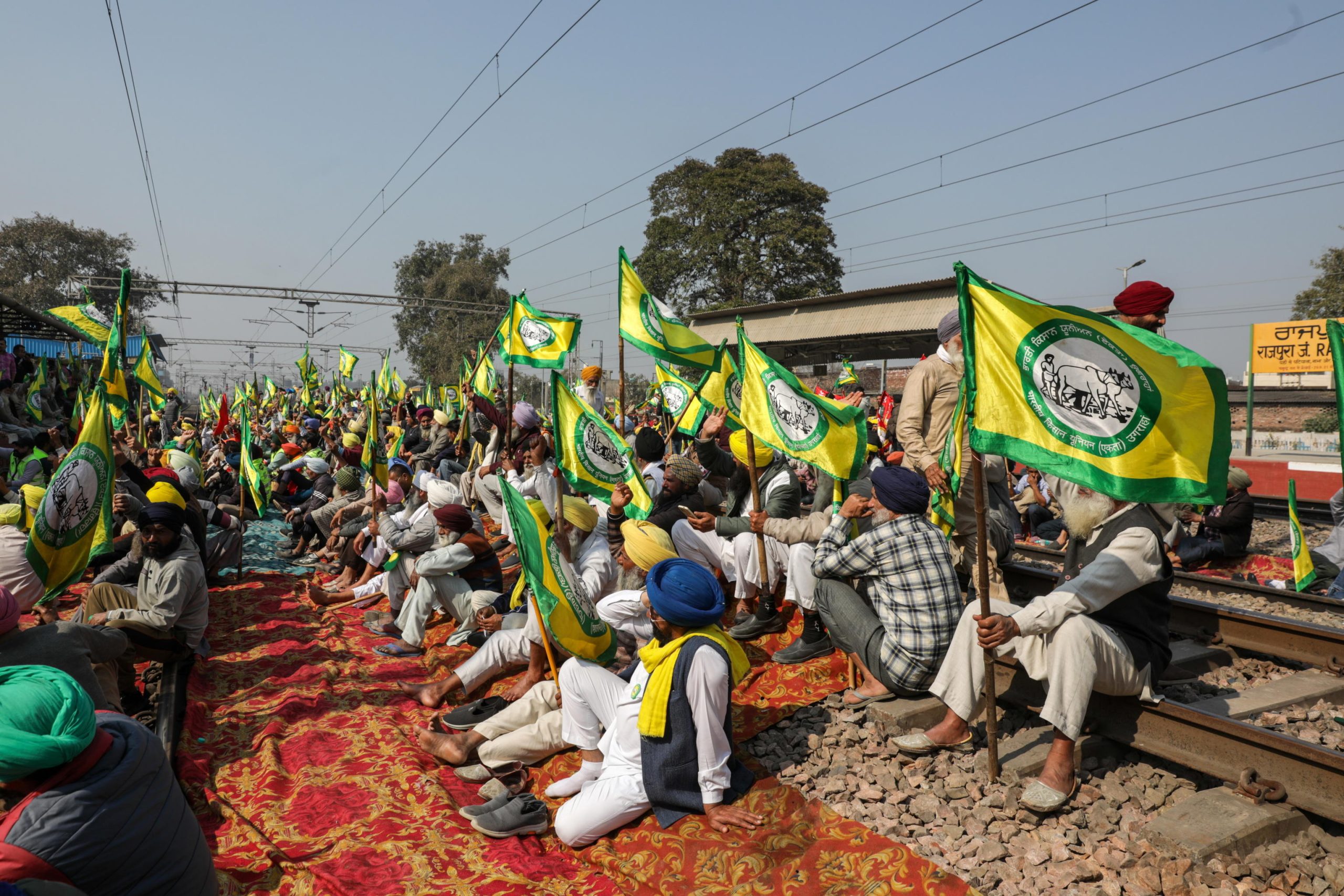 Agricoltori in protesta seduti sui binari ferroviari della stazione di Rajpura