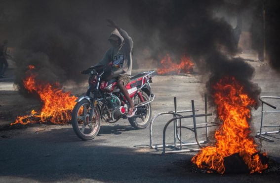 Una persona guida una motocicletta tra gli incendi delle strade