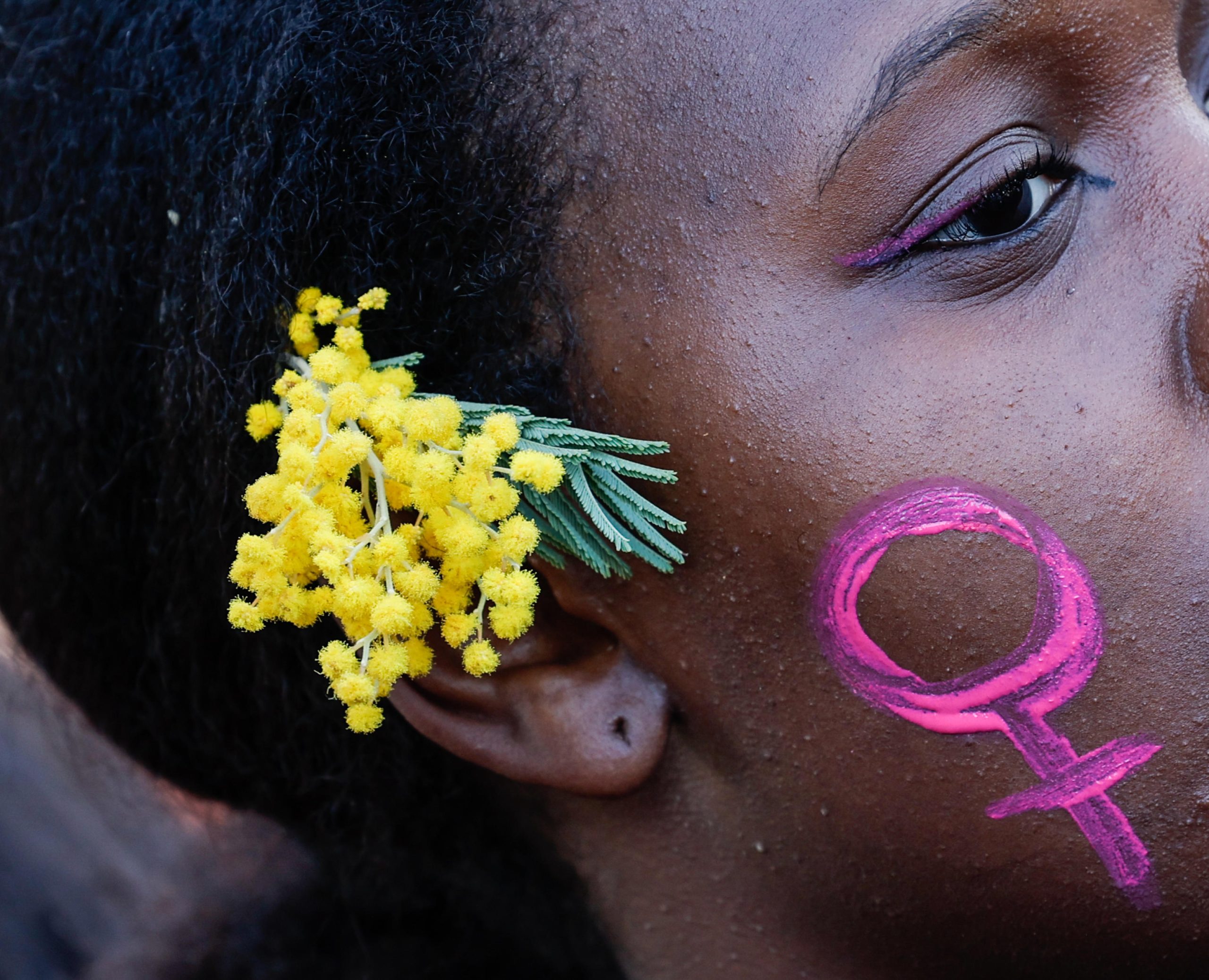 Una manifestante romana porta tra i capelli una mimosa, simbolo italiano della Giornata internazionale della donna