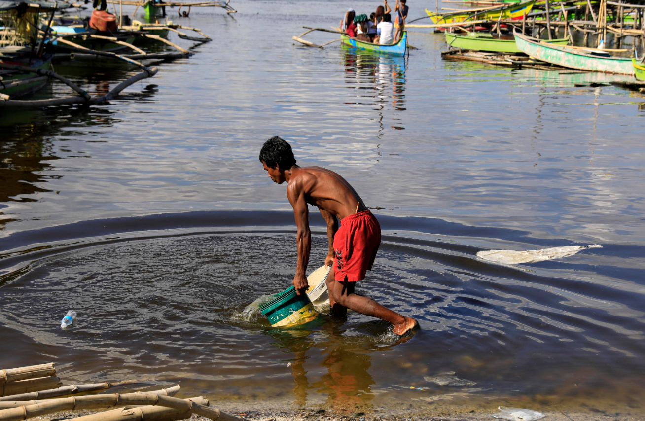 Un uomo raccoglie l'acqua con dei secchi a Bacoor City, nelle Filippine. Nel Paese circa 40 milioni di persone non hanno accesso a un approvvigionamento idrico