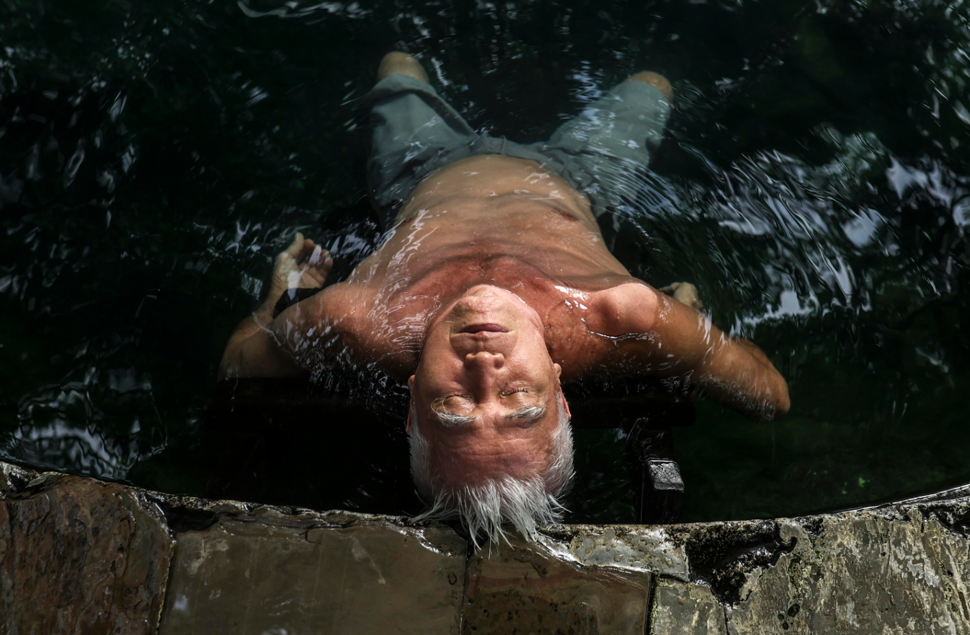 Un uomo si immerge in una sorgente calda fuori Kuala Lumpur, in Malesia