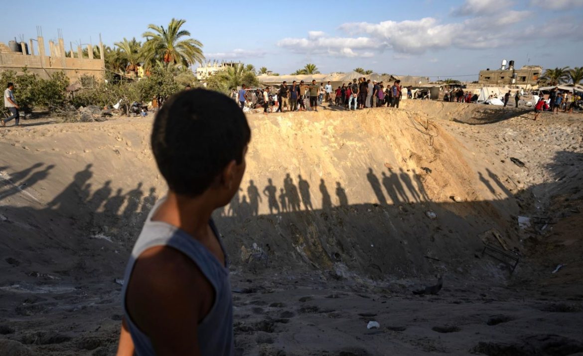 Un bambino palestinese osserva mentre gli altri ispezionano un cratere alla ricerca di persone scomparse | foto Ansa