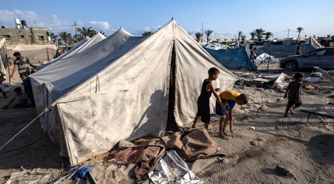 Dei bambini palestinesi fuori da una tenda aspettano mentre gli altri cercano le persone scomparse